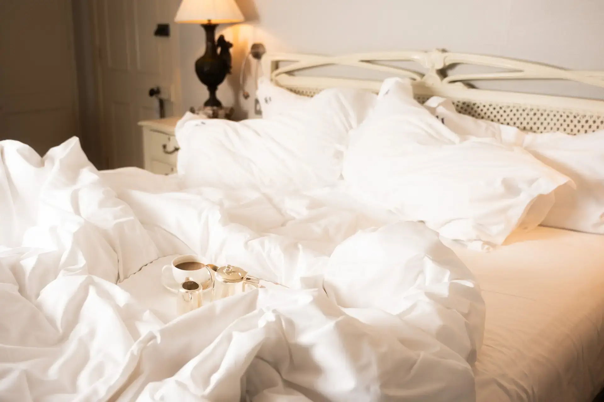bed with white sheets and silver tea set
